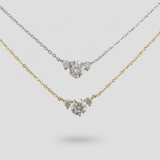 Two diamond necklaces on a textured surface with an ornate gold frame.