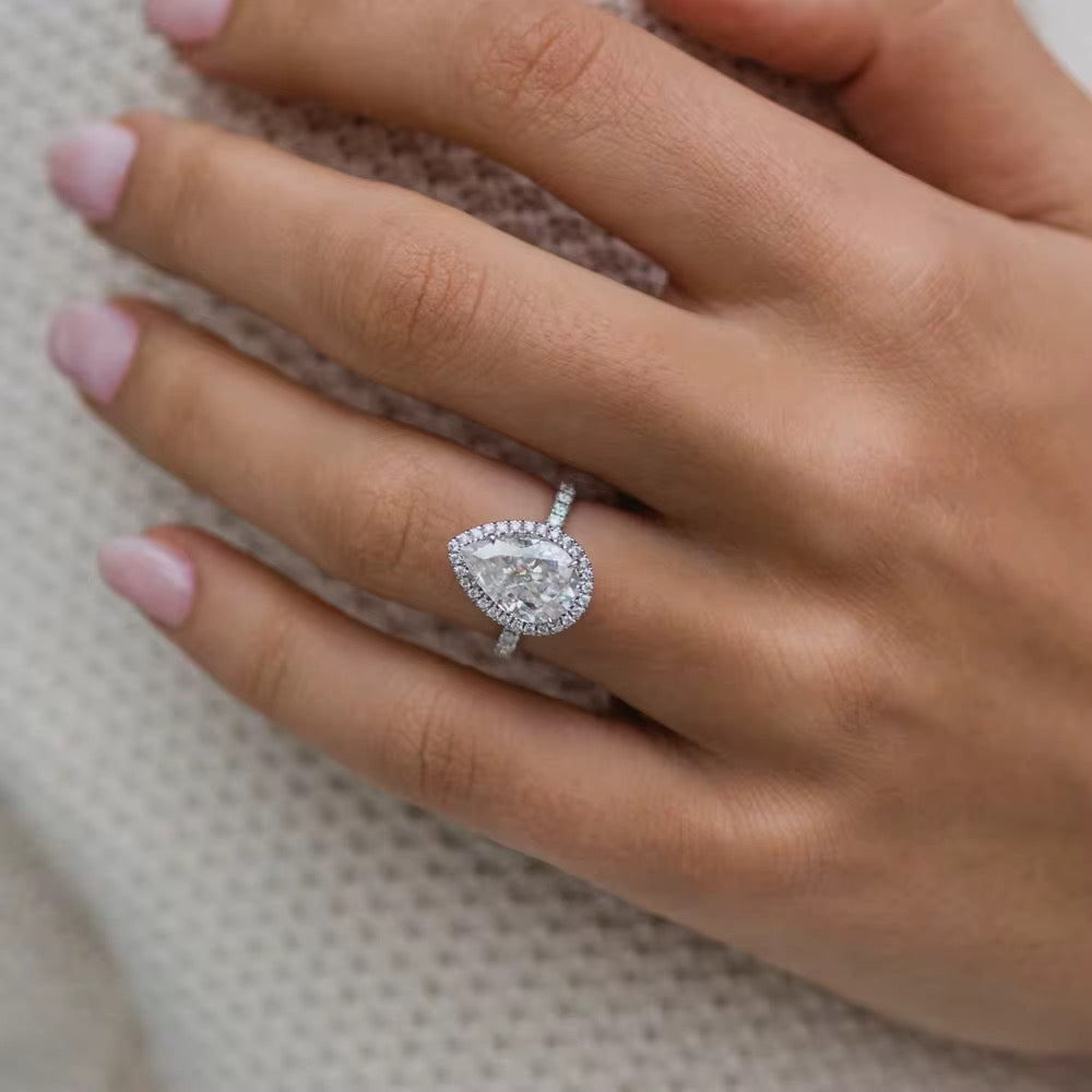 Close-up of a hand wearing a diamond ring on a neutral background