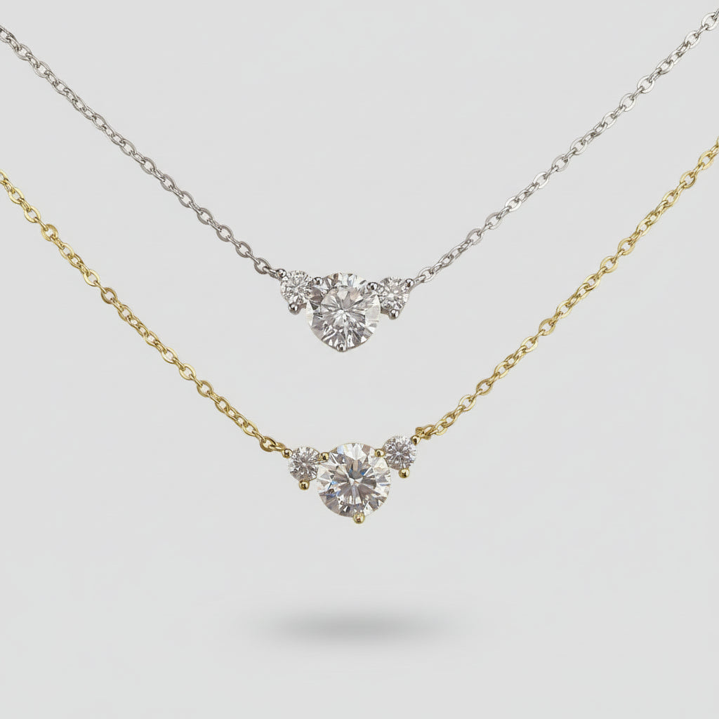 Two diamond necklaces on a textured surface with an ornate gold frame.