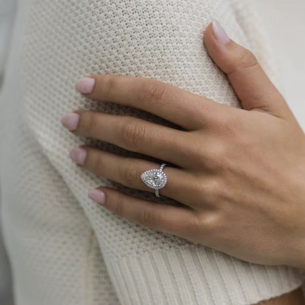 Hand wearing a diamond ring on a textured surface