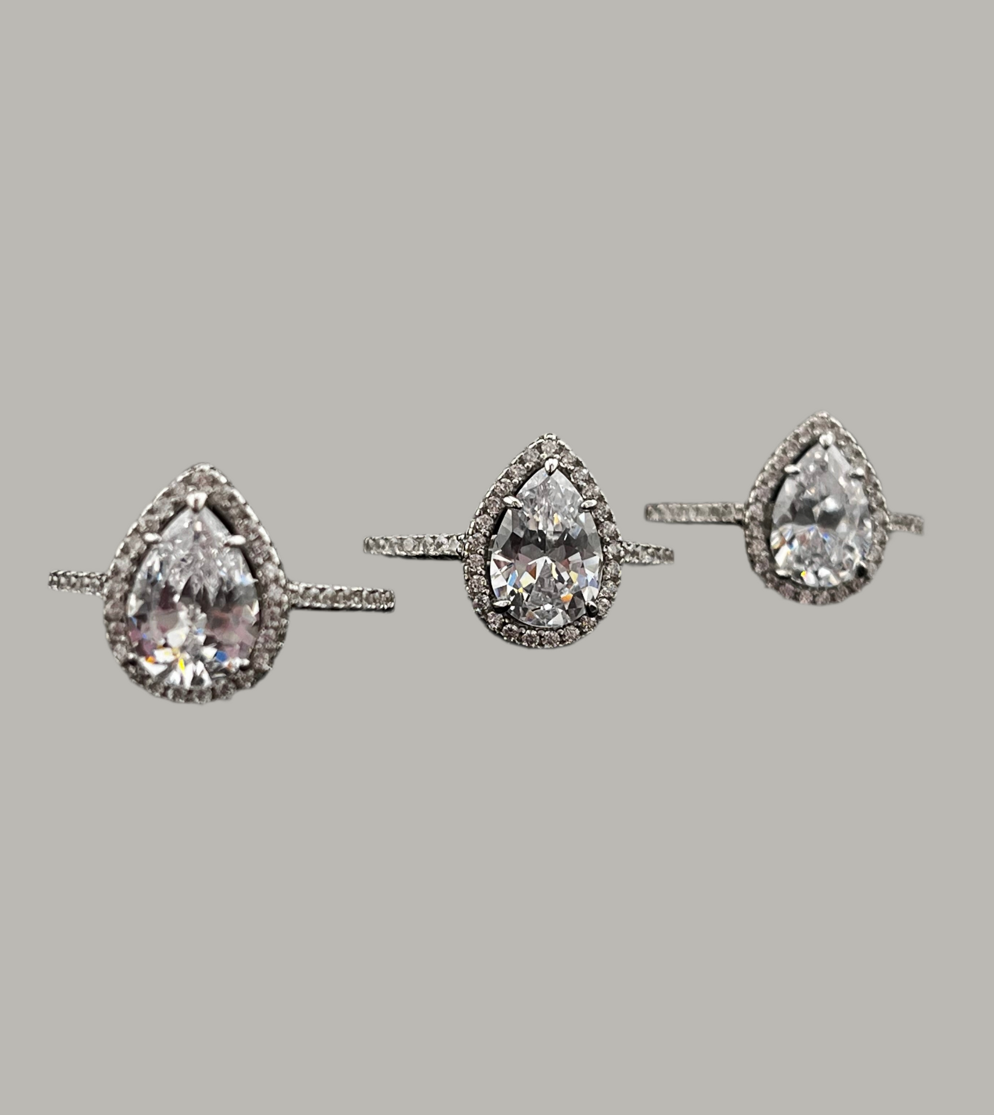 Pair of teardrop-shaped diamond earrings on a gray background