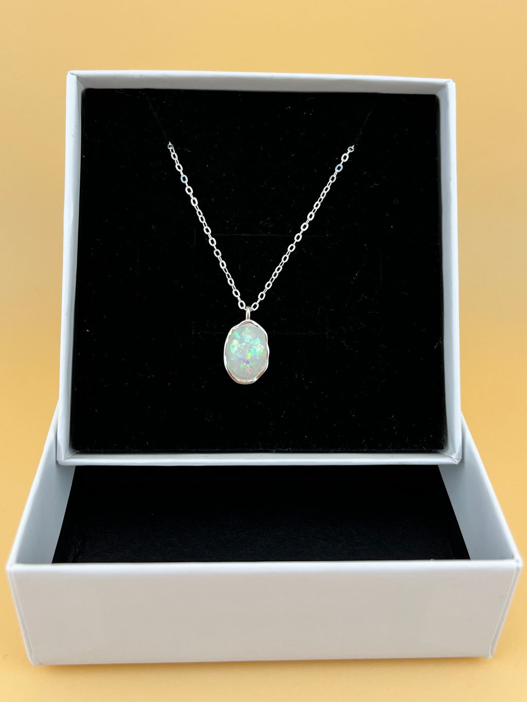 Necklace with a pendant in a black box on a beige background