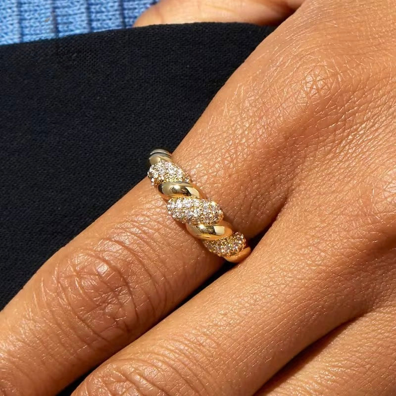 Gold and diamond ring on a person's finger with a blurred background