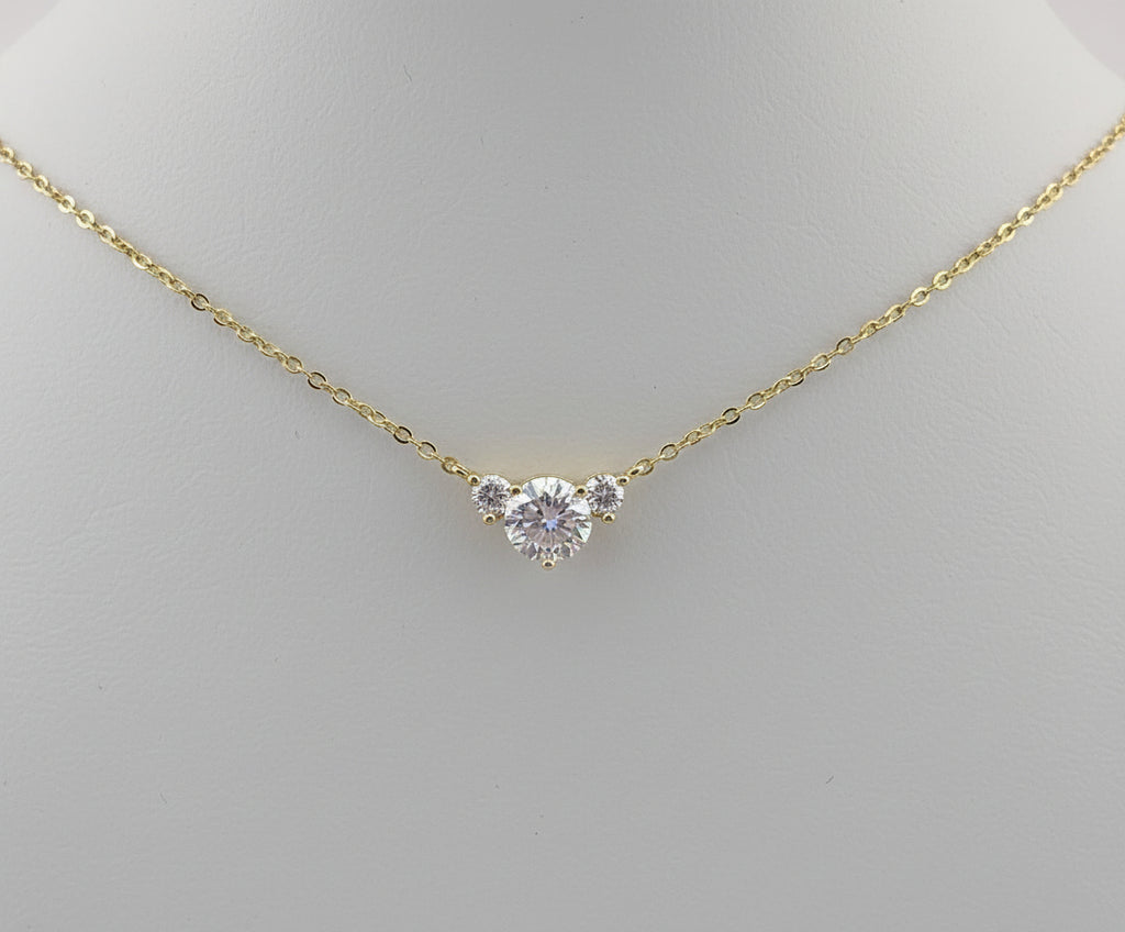 Gold necklace with a diamond pendant displayed in an ornate gold frame.