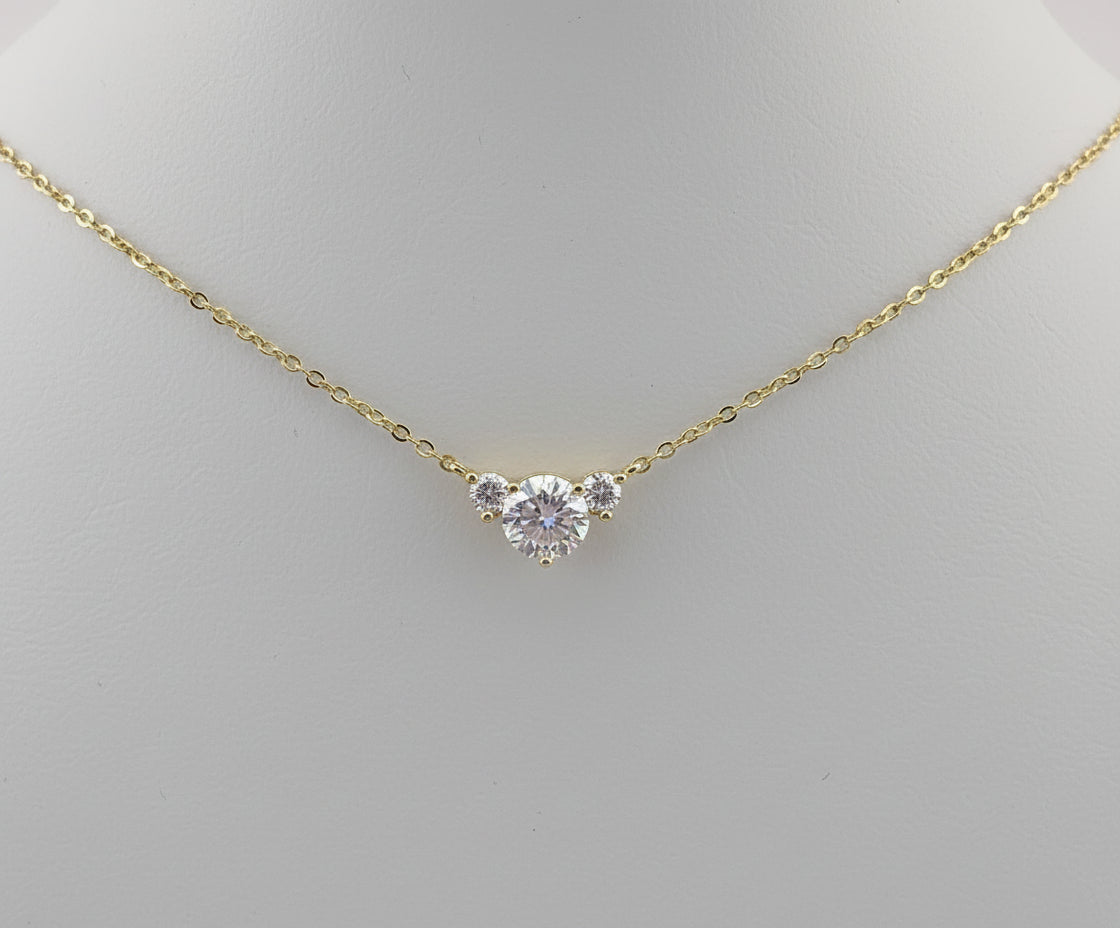 Gold necklace with a diamond pendant displayed in an ornate gold frame.